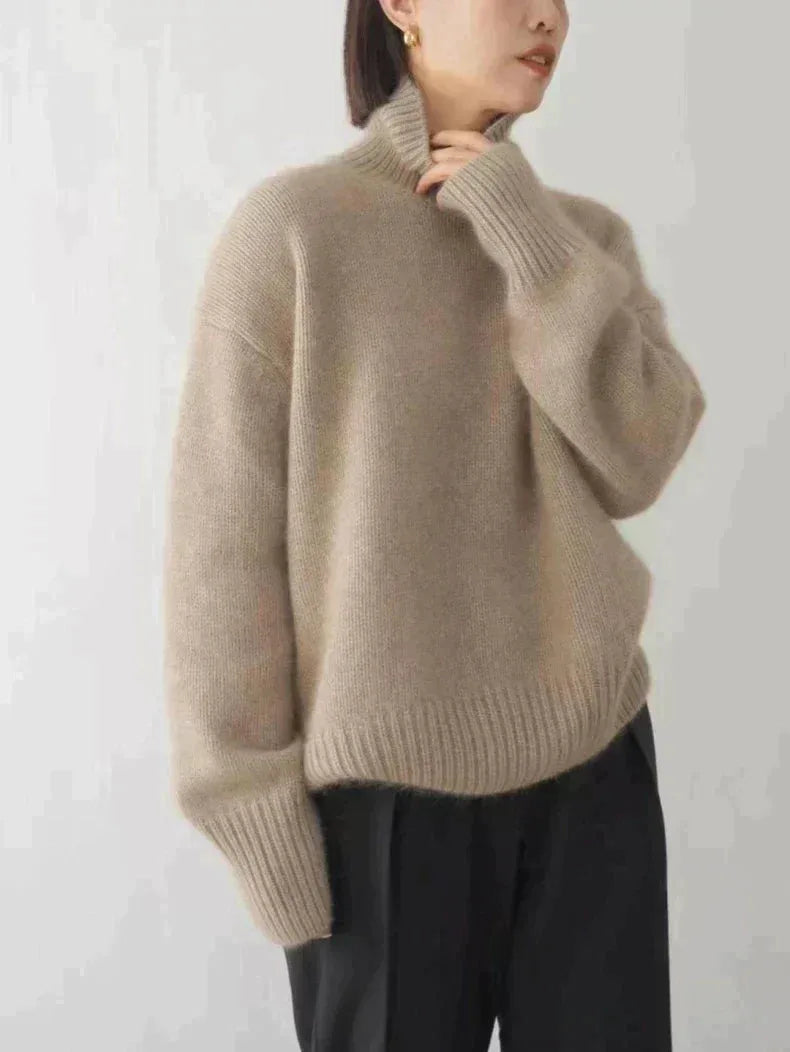 Taupe polo neck jumper shown from the side with ribbed cuffs, worn over black trousers