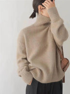 Back and side view of a taupe polo neck jumper with dropped shoulders and a brown crossbody bag