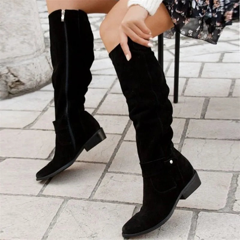 Close-up of black suede slouch boots showing side zip fastening and rounded toe