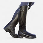 Pair of sleek black leather knee-high boots shown in walking motion against a plain backdrop