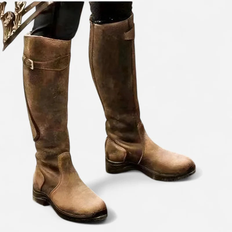 Tan brown knee-high leather boots with buckle strap, front angled view showing rounded toe and low heel