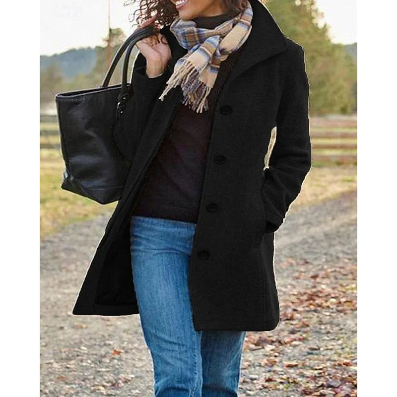 Black wool coat with turndown collar, button-front and front pockets, worn open over a dark jumper on a country path