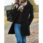 Black wool coat with turndown collar, button-front and front pockets, worn open over a dark jumper on a country path