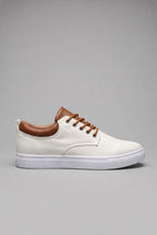 Side profile of a woven lace-up trainer on a white cupsole against a plain grey backdrop