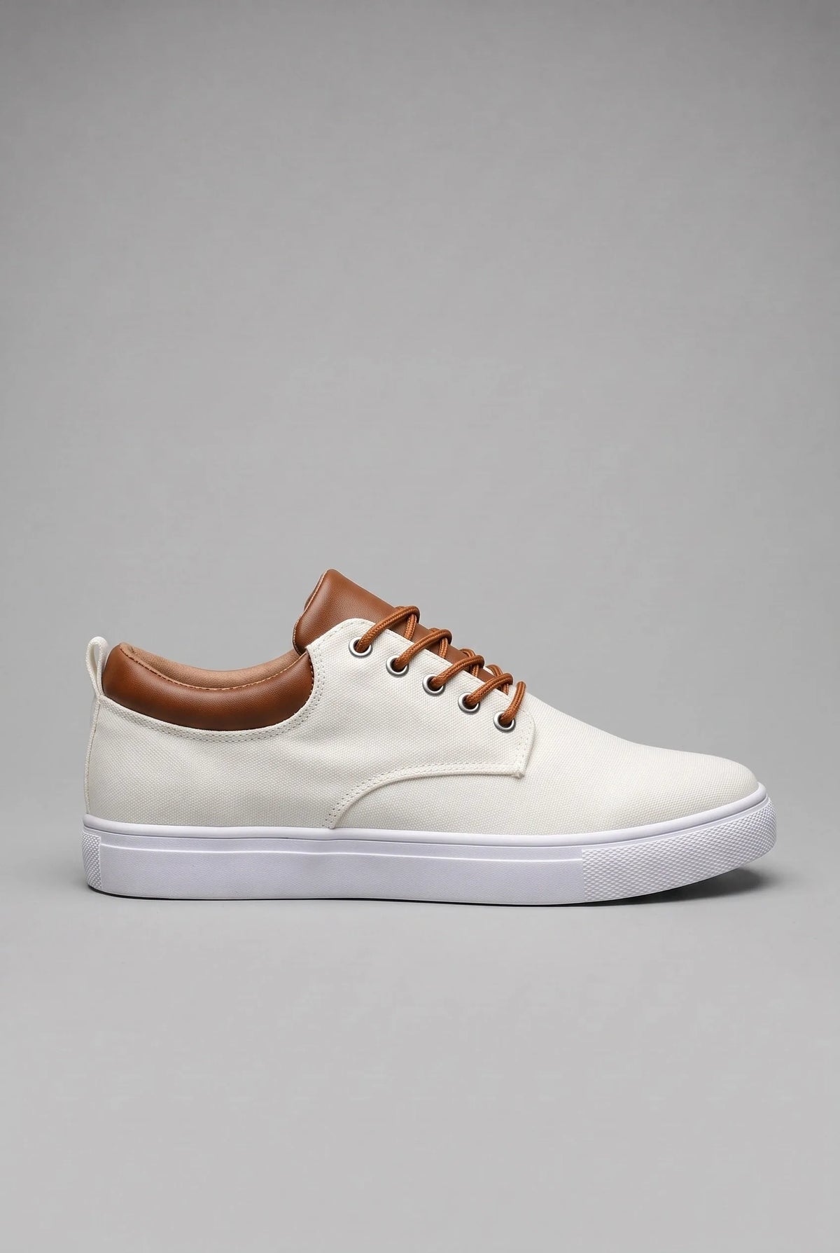 Side profile of a woven lace-up trainer on a white cupsole against a plain grey backdrop