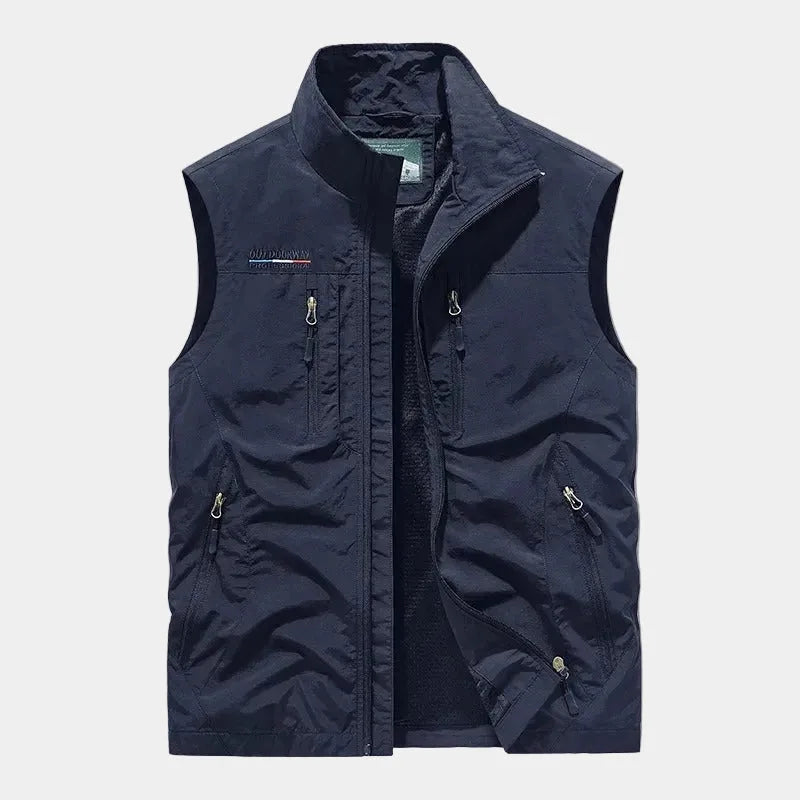 Navy zip-front gilet with stand collar and multiple zipped pockets, worn open to show inner lining