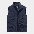 Navy zip-front gilet with stand collar and multiple zipped pockets, worn open to show inner lining
