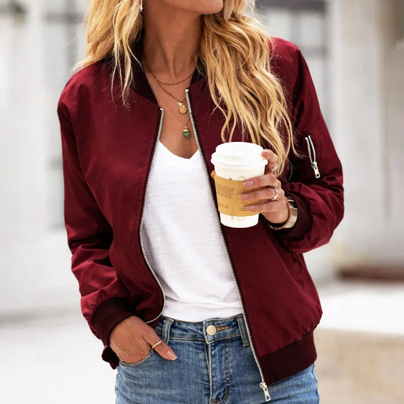 Close-up front view of a burgundy zip-up bomber jacket worn open over a white top, showing satin-look fabric sheen